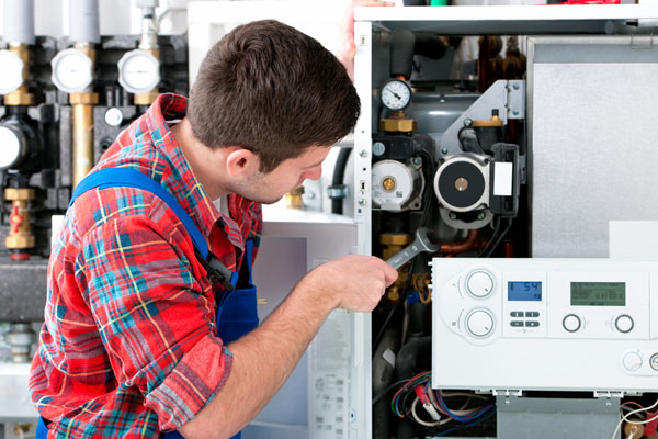 HVAC technician inspecting and repairing boiler controls in Midvale