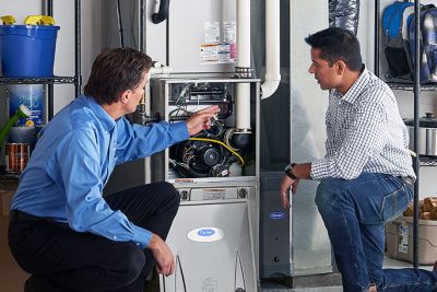 65df8c11f3e4c468cbd351a5_furnace repair vs replacement – Copy HVAC technician explaining furnace repair and maintenance to a homeowner in Midvale, UT